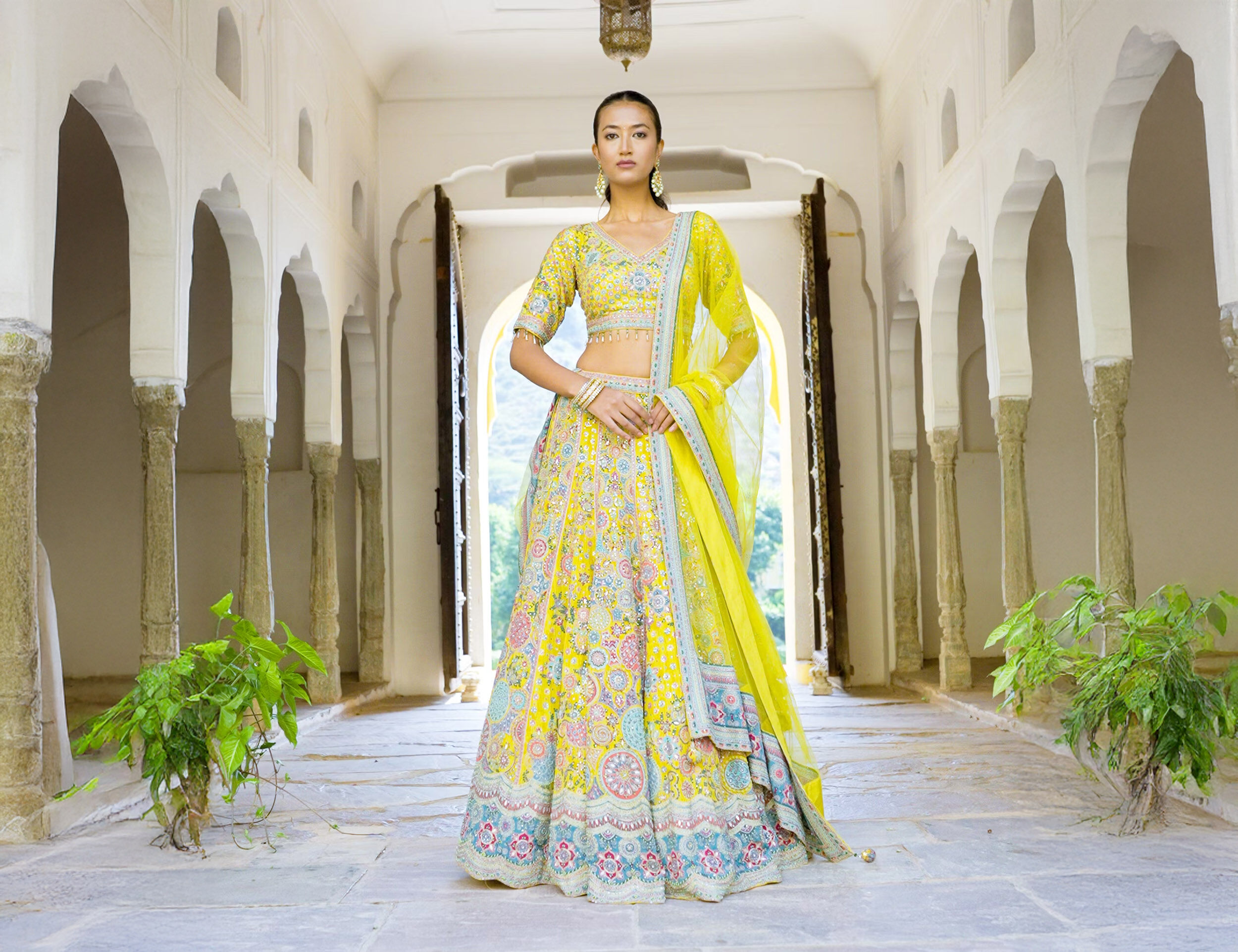 A women flaunting her yellow net lehenga for mehedi ceremony